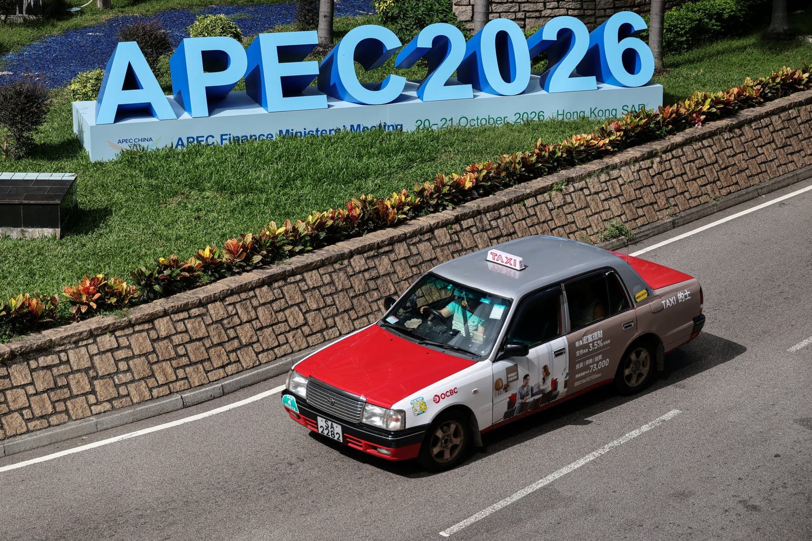 A taxi drives past a sign for the APEC Finance Ministers' Meeting in Hong Kong, China, October 20, 2026. REUTERS/Tyrone Siu