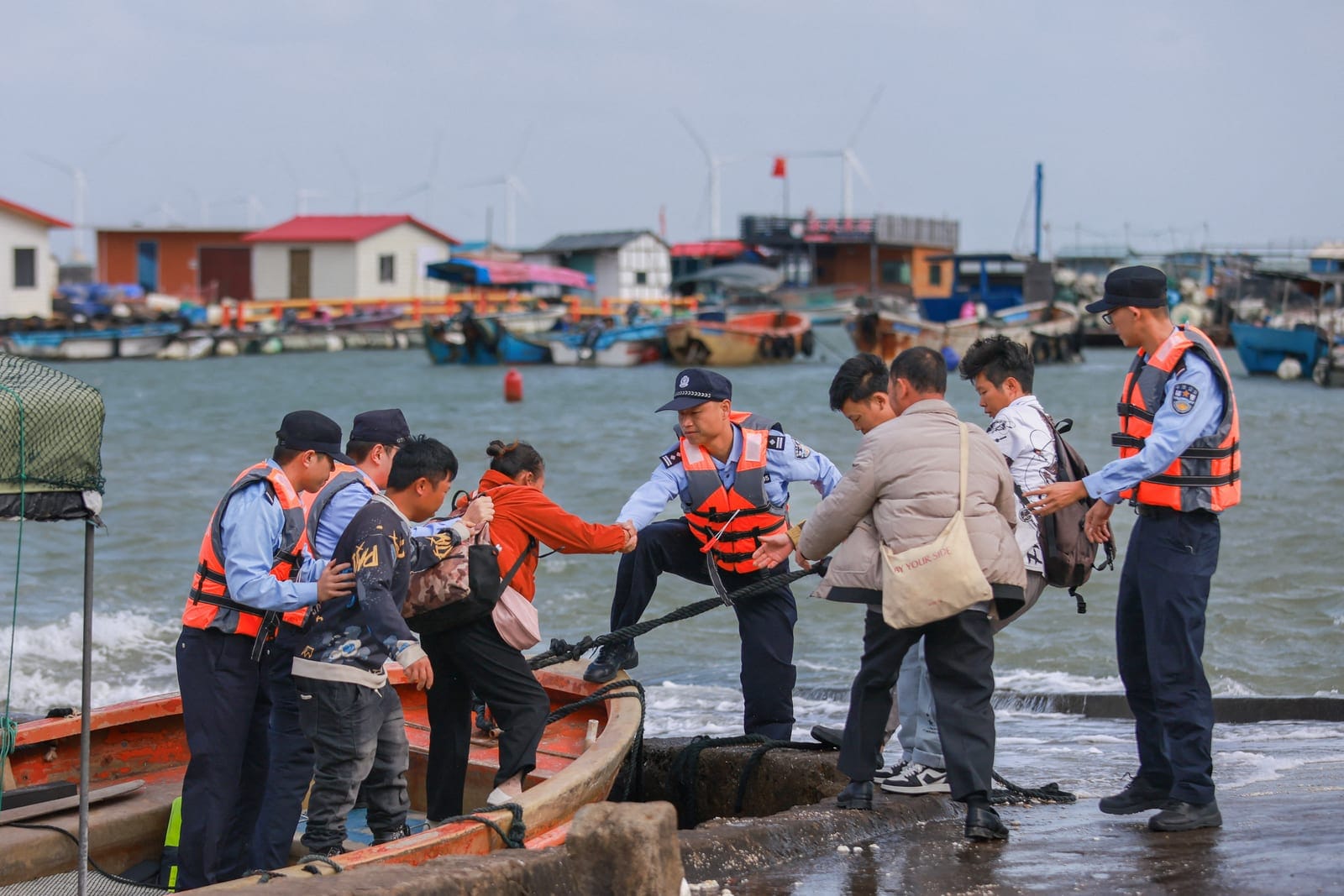 Police officers help aquaculture workers come ashore from a boat as they evacuate as Typhoon Champi approaches, at a pier in Longtou village, Pingtan, Fujian province, China October 22, 2026. cnsphoto via REUTERS REUTERS/cnsphoto