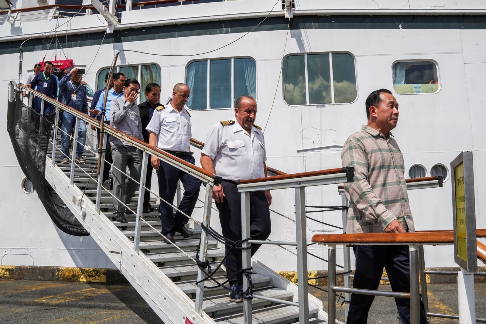 Captain Emanuele Giudice of the Villa Vie Odyssey cruise ship and Cambodia's Minister of Tourism Huot Hak disembark the vessel, which is docked at Sihanoukville Autonomous Port after permanent residents living aboard the vessel were forced to disemba