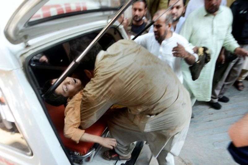 Rescue workers carry a boy injured after a school roof collapse in Peshawar