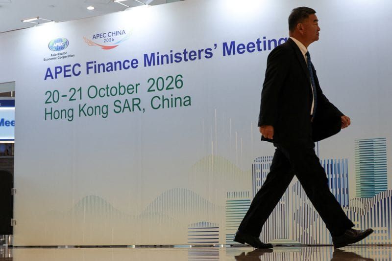 A man walks past a sign for the APEC Finance Ministers' Meeting in Hong Kong