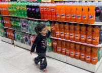 A child walks past a display of soft drink bottles inside a supermarket in Mumbai