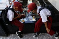 Students eat from plastic containers at a school in the fishing village of Torosiaje
