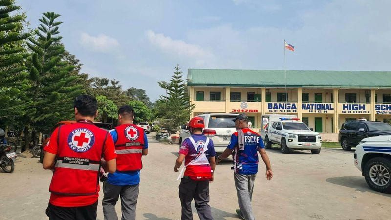 Emergency personnel walk at a site of a deadly shooting at a school in Banga