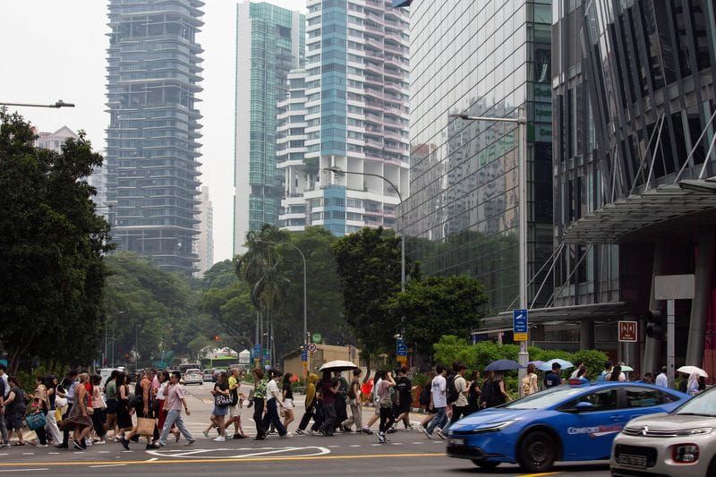 People cross the road as residential and commercial buildings are shrouded by haze in Orchard Road in Singapore