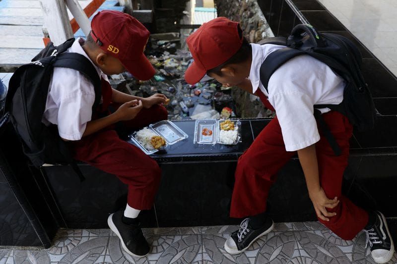 Students eat from plastic containers at a school in the fishing village of Torosiaje