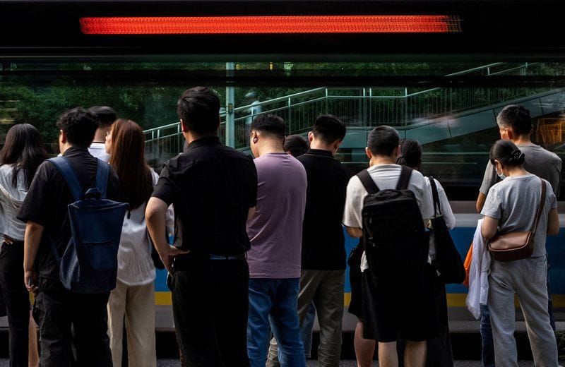 FILE PHOTO: People queue to board a commuter bus after work in Beijing