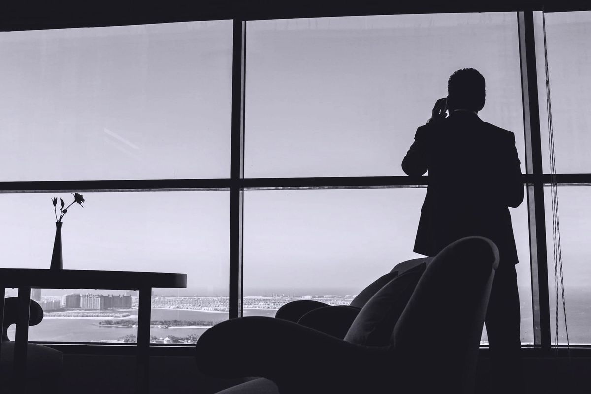 Hombre en un despacho con vistas al mar hablando por teléfono 