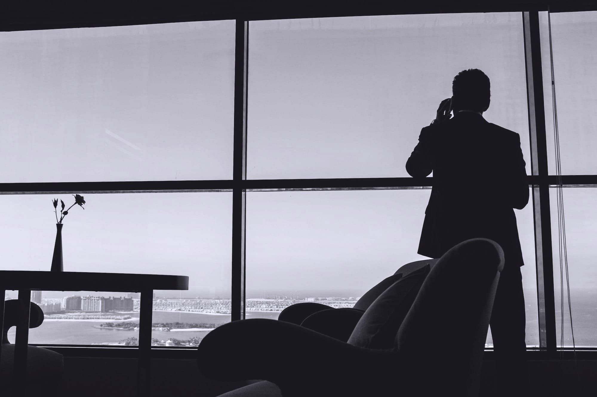 Hombre en un despacho con vistas al mar hablando por teléfono 