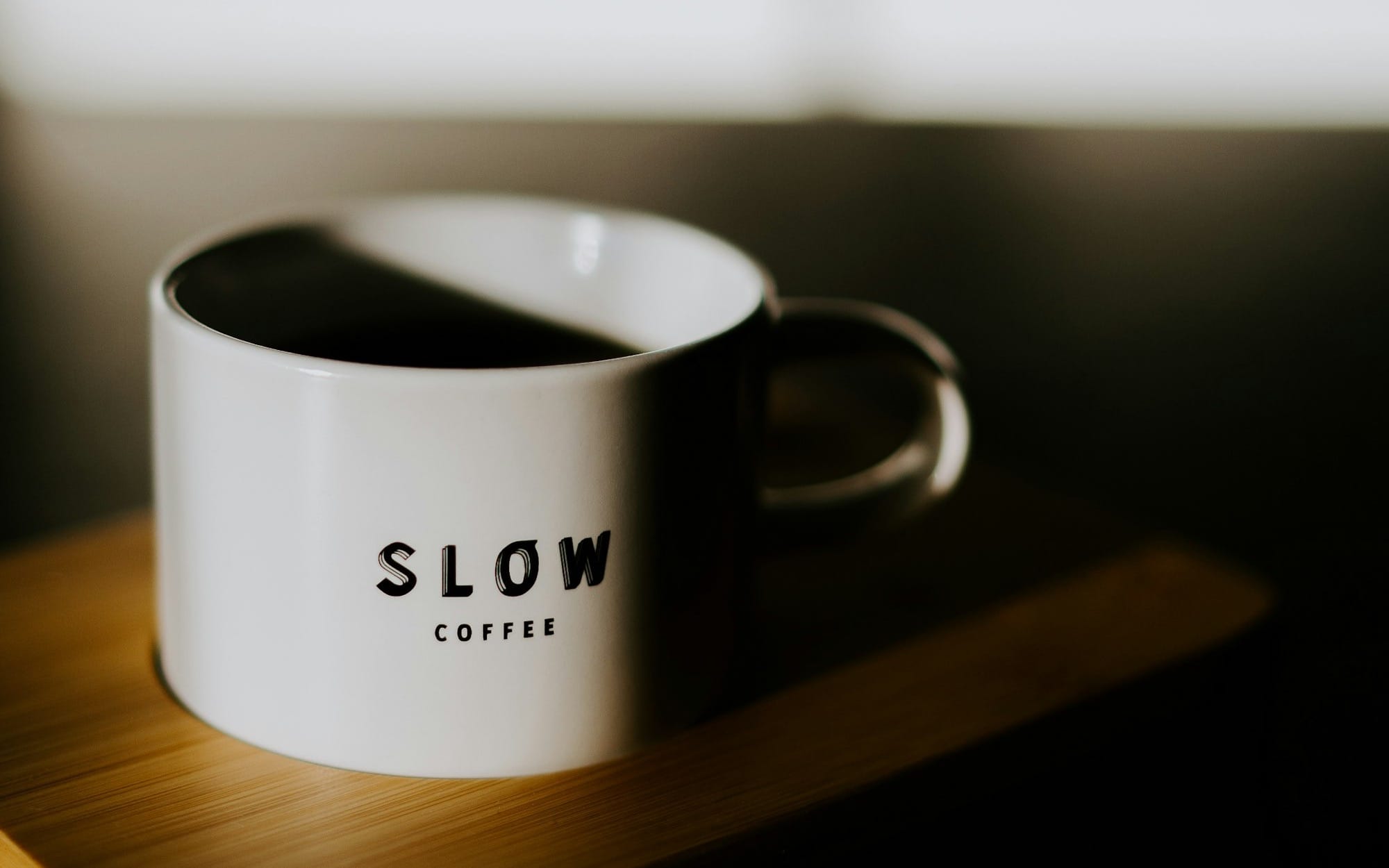 a white coffee cup sitting on top of a wooden tray