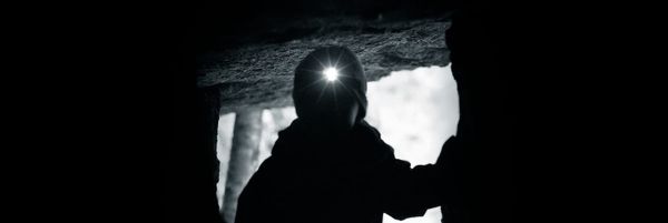 Lapsi luolan suulla otsalampun kanssa. 