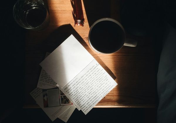 An open notebook and pen on a wooden table in morning light.