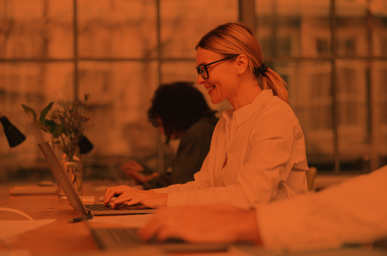 Young female employee smiling while typing on her laptop at work. 