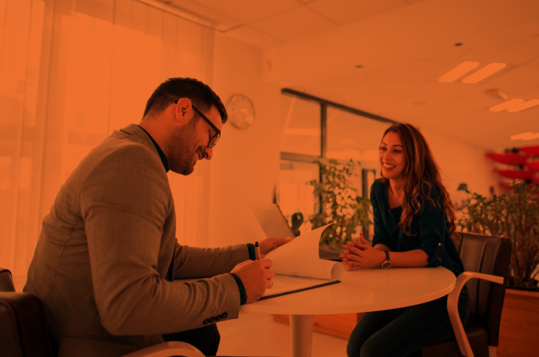Professional young man answering questions and a young woman sitting across the table smiling. 