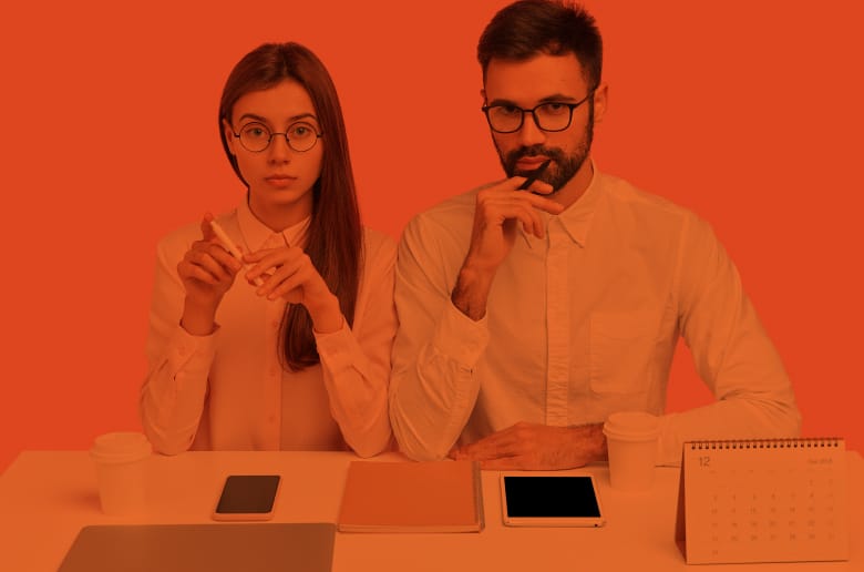 Two professional individuals sitting on a desk waiting for an interview.