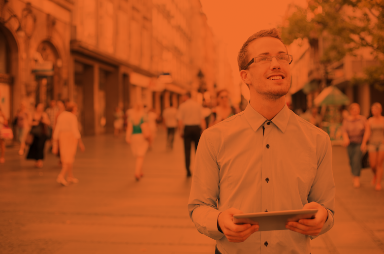 Guy walking around a city holding a tablet. 