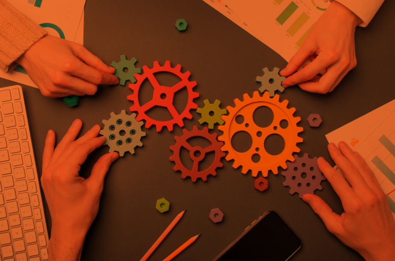 Four hands assembling something with colorful settings. 