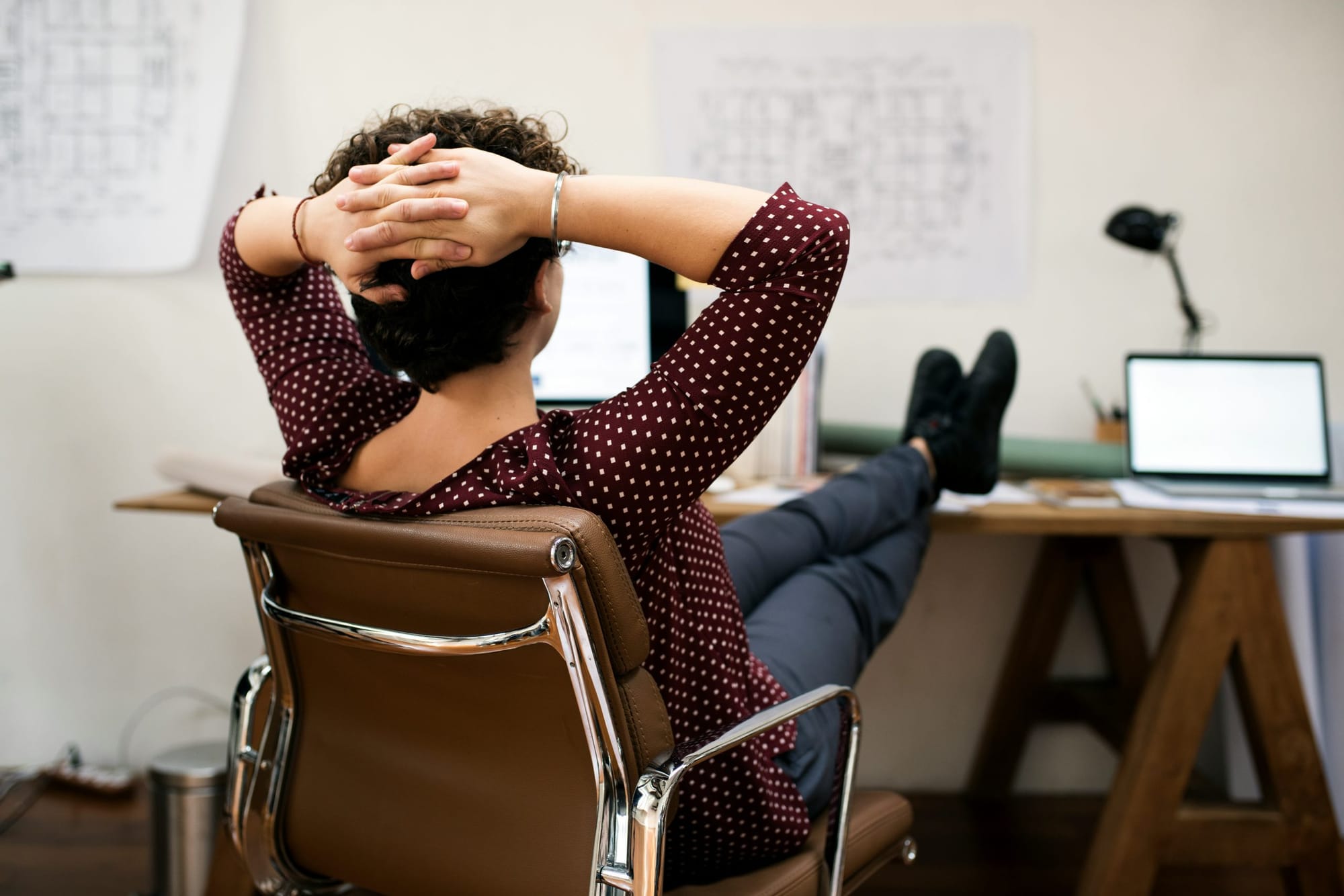 Young woman in an office having her legs on the office desk. 