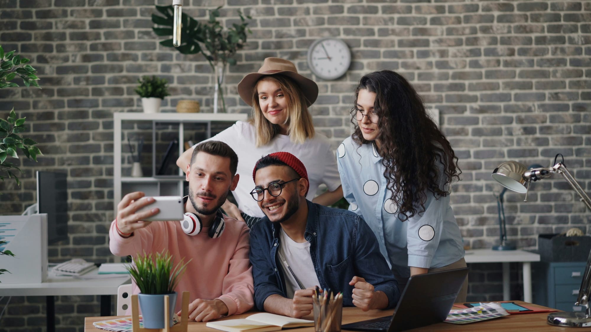 Young coworkers smiling in a creative office, showing Gen Z workplace culture and collaboration.