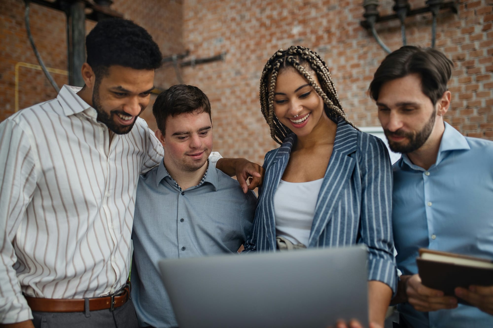 Diverse colleagues collaborating around a laptop in an inclusive modern workplace.