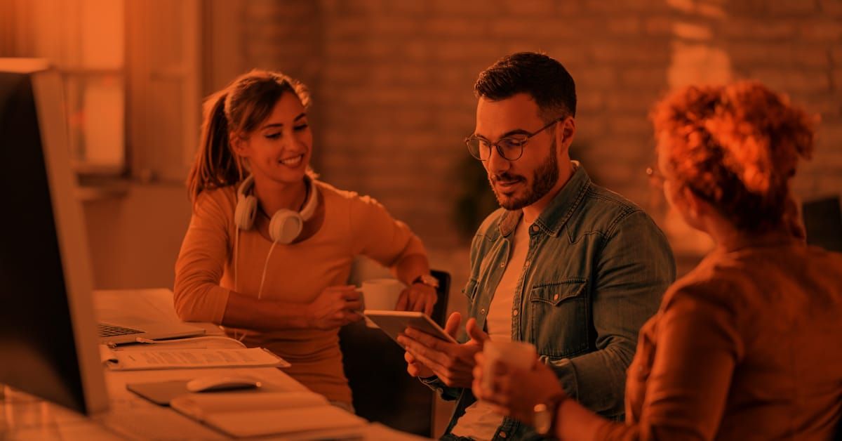 Team of three discussing while a man holds a tablet.