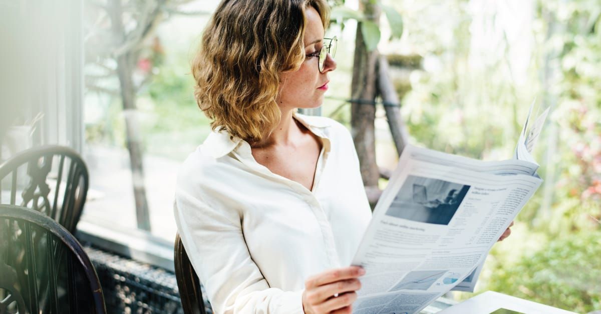 Woman sitting on a café and reading a newspaper. 