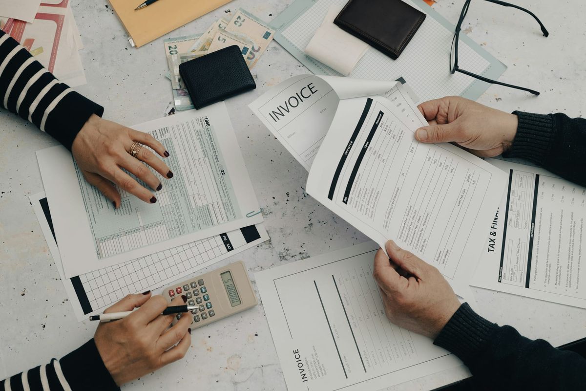 Accounting professionals reviewing invoices and financial documents at a desk.