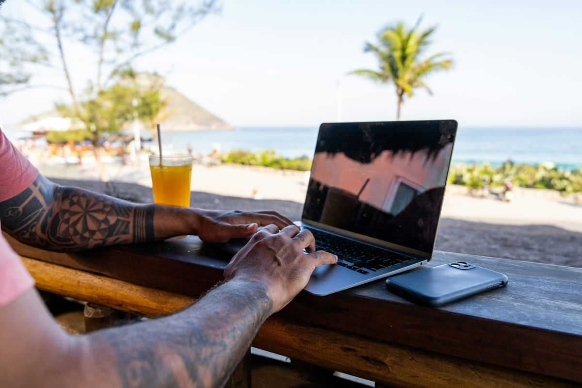 Person using a laptop by the beach, planning their next career move during summer.