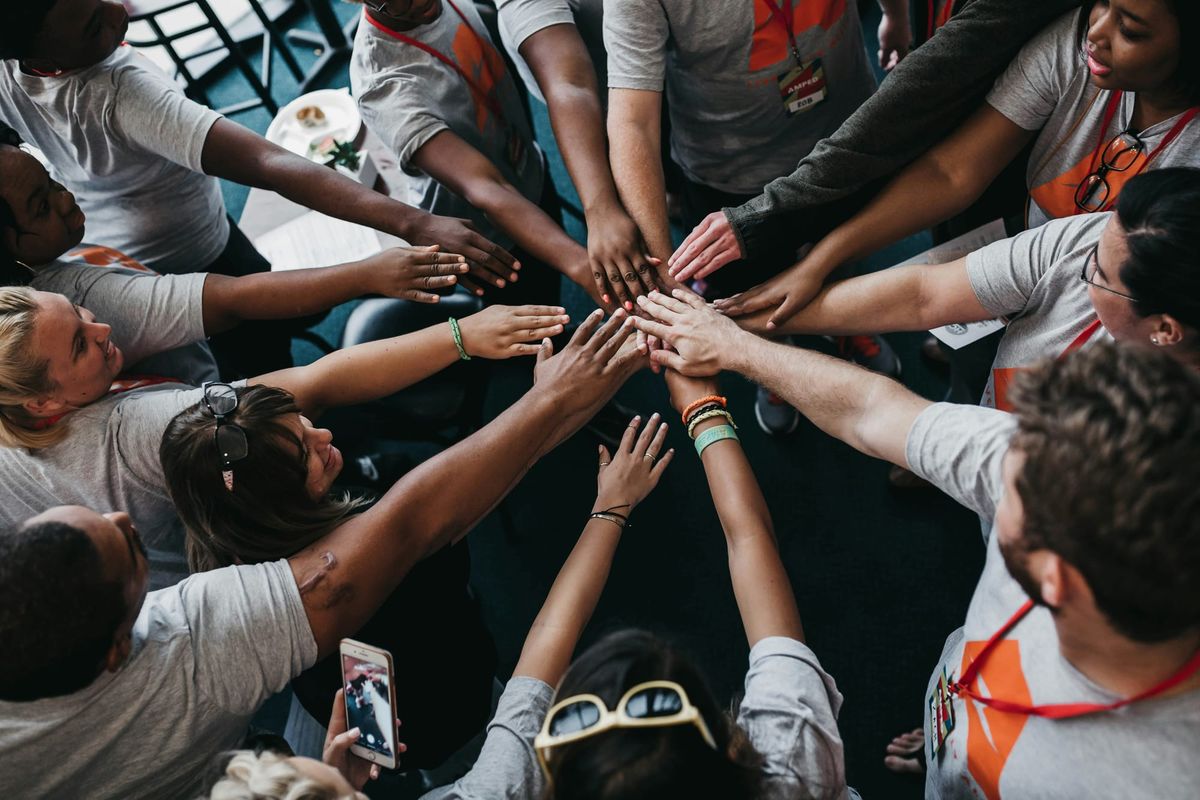 Diverse team joining hands together, representing equality, inclusion and diversity in the workplace.