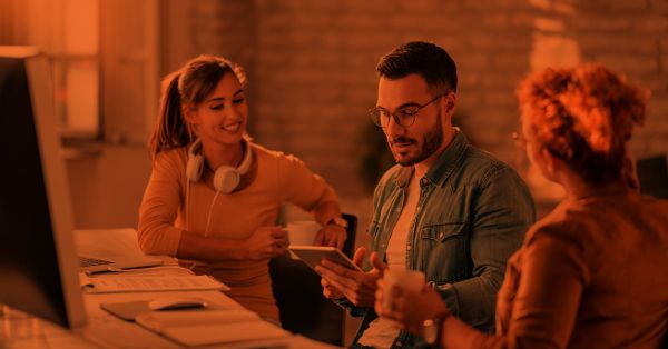 Team of three discussing while a man holds a tablet.