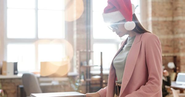 Woman in office wearing a Santa hat. 