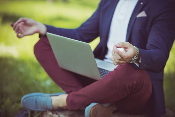 Professional sitting outdoors with a laptop, representing work-life balance and personal wellbeing.