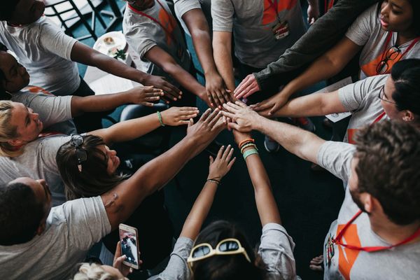 Diverse team joining hands together, representing equality, inclusion and diversity in the workplace.