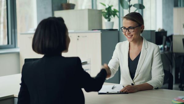 Professionals shaking hands after a successful job interview during the September hiring season.