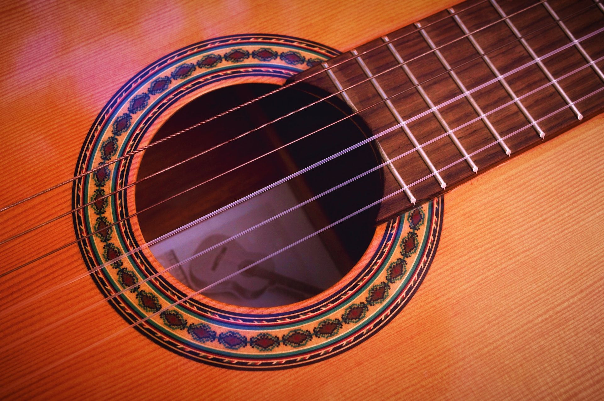 A close-up of a classical guitar with strings and sound hole