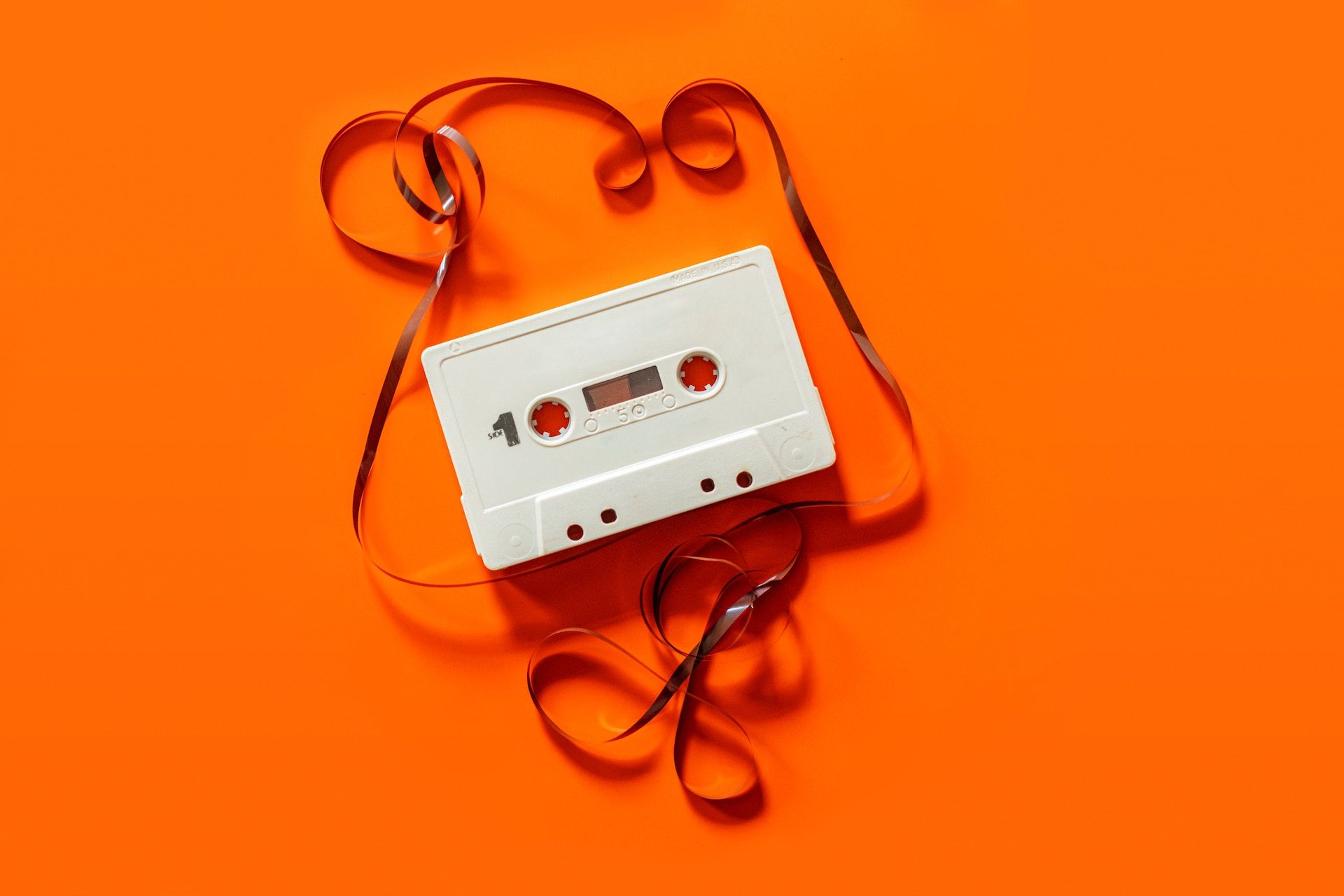 Unmarked and unspooled cassette tape on orange background