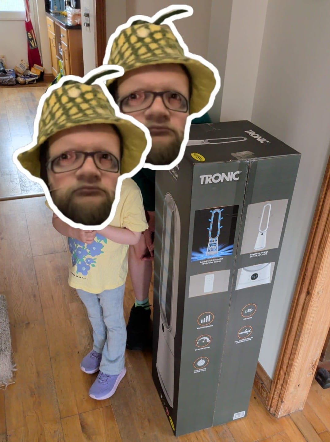 A photo of a boxed floor-standing fan next to my two children. The box is about the same height as my five-year-old.