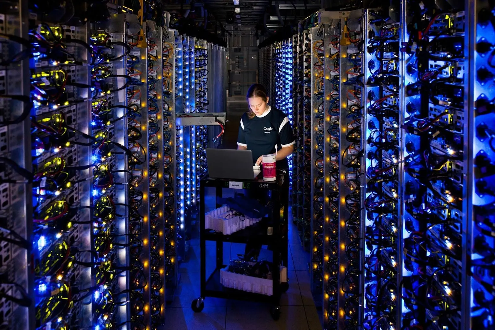 A Google Cloud worker diagnoses a problem in the middle of a large rack of servers.