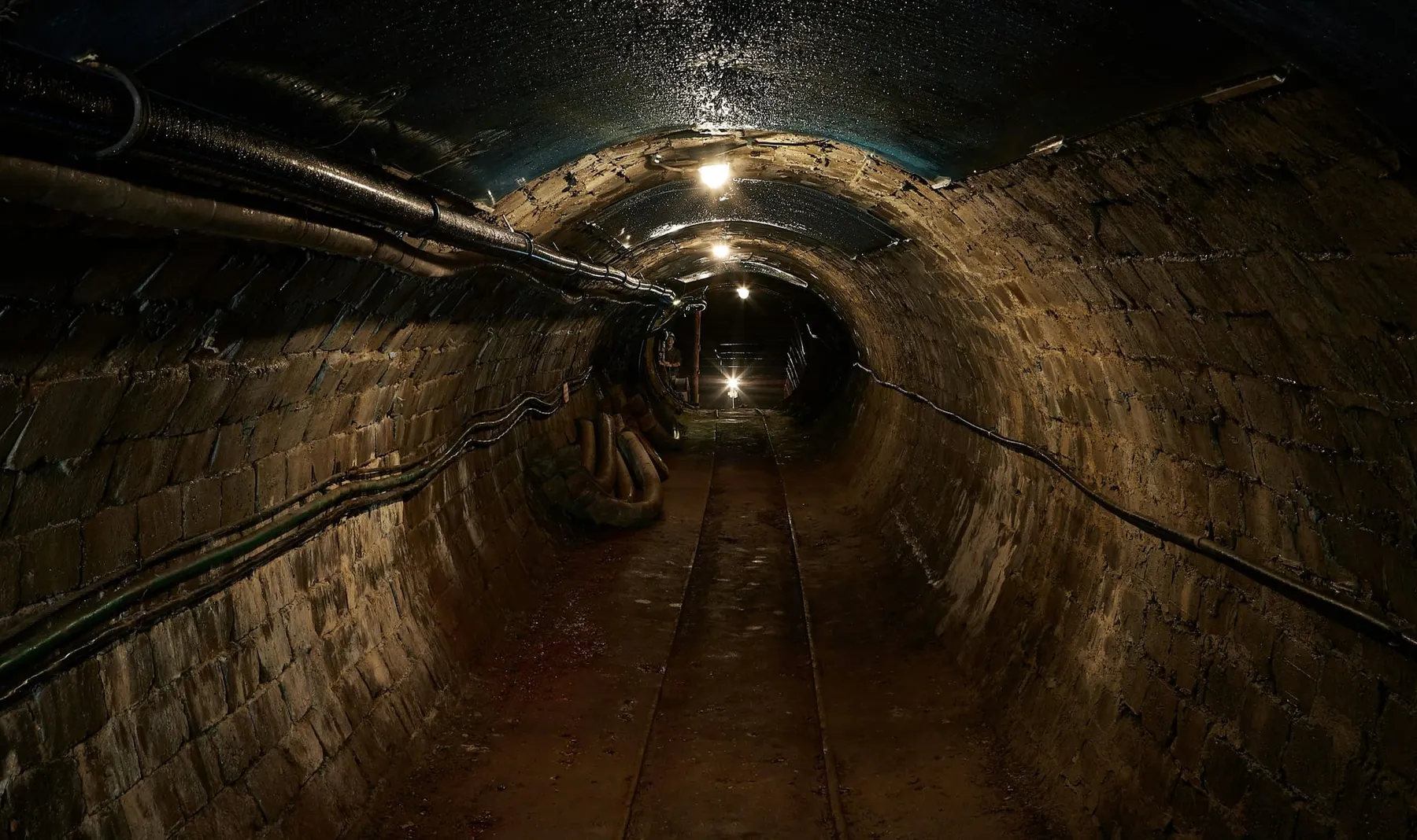 An empty sewer with cables and pipes running along it, Anglian Water will install up to 60,000 sensors in its sewer networ