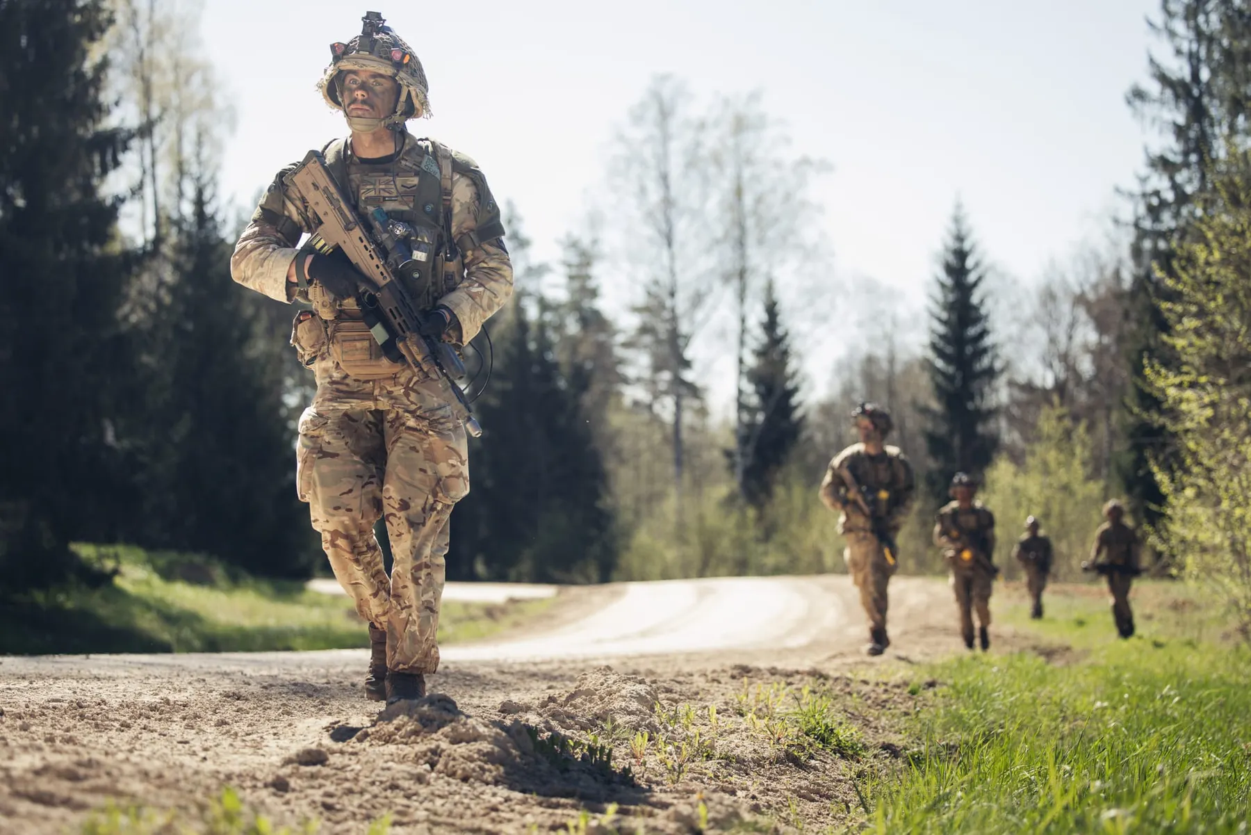 A soldier walks through a forest holding a gun as others follow behind him. The UK military's cyber risk was deemed "intolerable" by a defence spending review