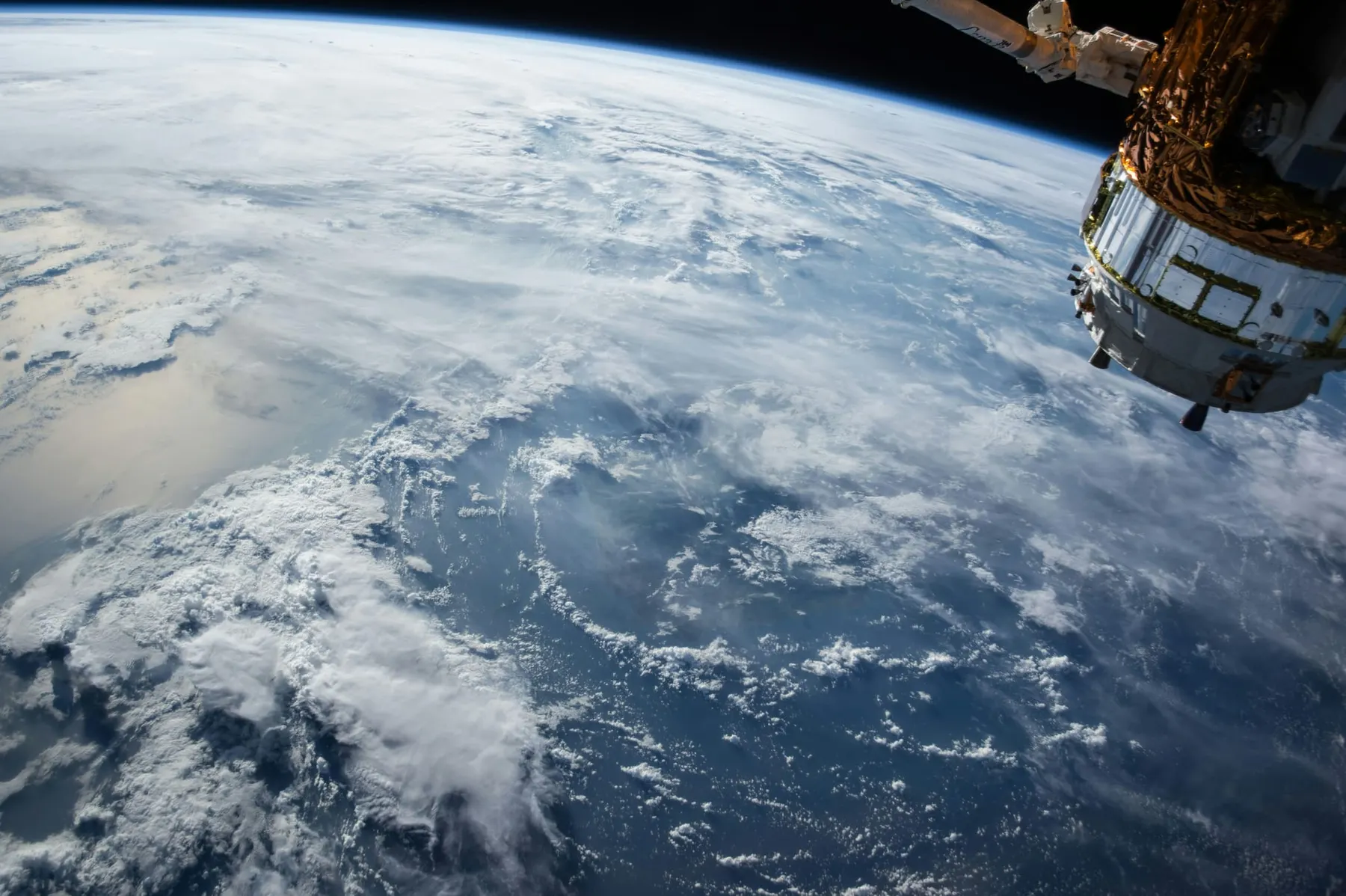 A satellite orbiting the earth, clouds can be seen over the ocean below. The orbital data centre sector wants to bring data centres up to space