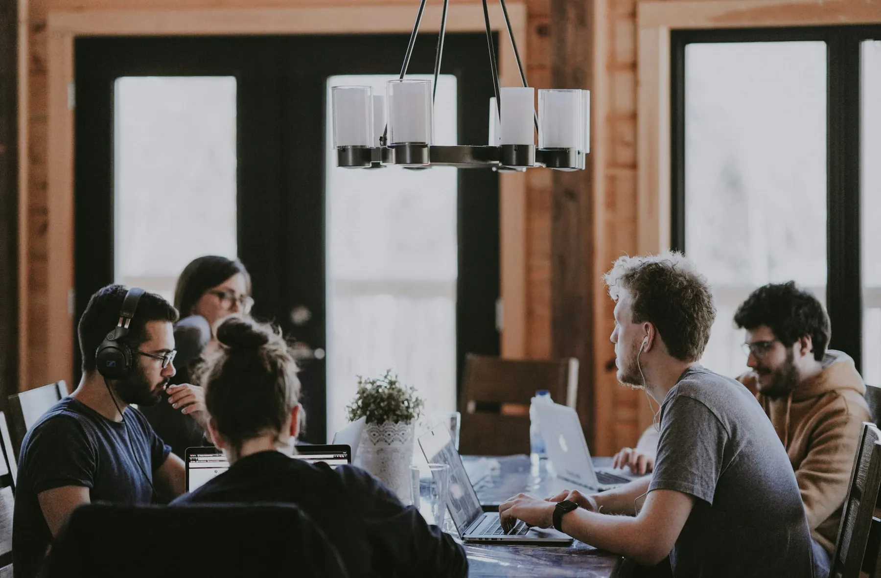A team of people sit on laptops around a table. Start up news this week includes rounds from FieldAI and Nuro.