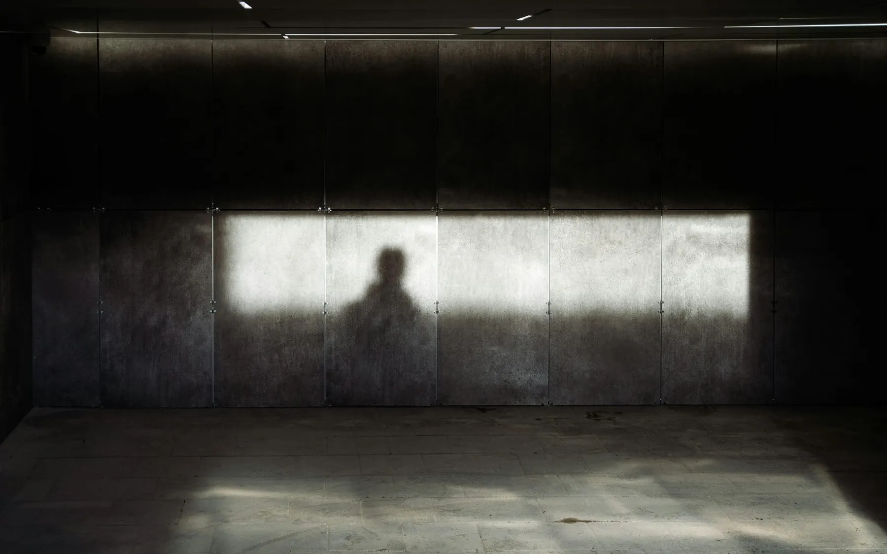 The shadow of a person's upper body on a metal wall. WhatsApp patched a zero click bug tied to a spyware campaign