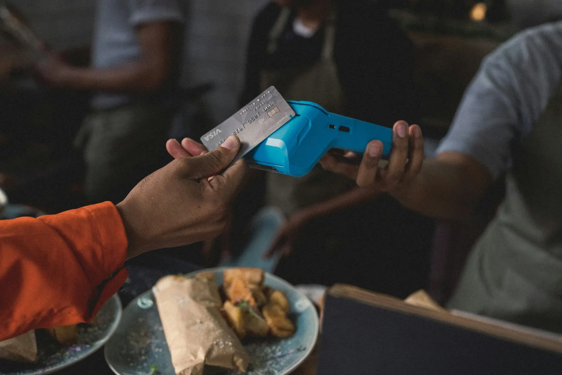 A person taps a Visa credit card on a payments terminal. Visa is working on agentic commerce with Google