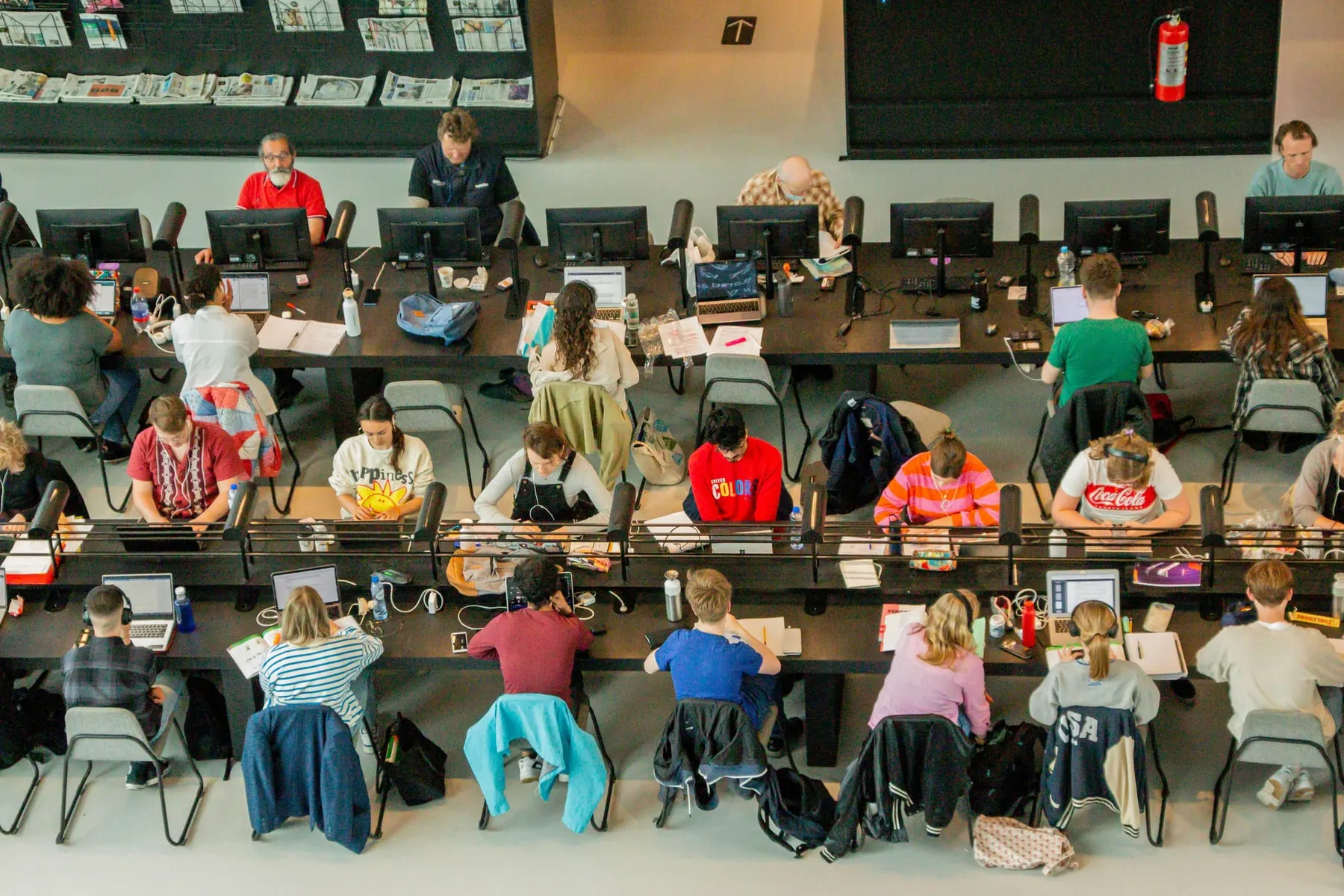 A group of people sit at long tables on laptops. AWS is expanding its team of forward deployed engineers