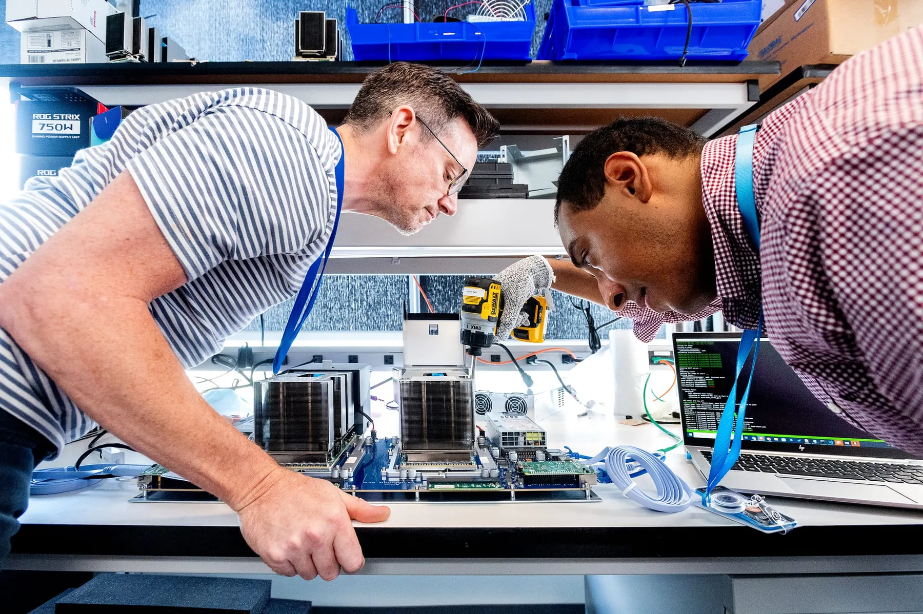 Two chip design workers look at an electrical model at a laboratory work bench.