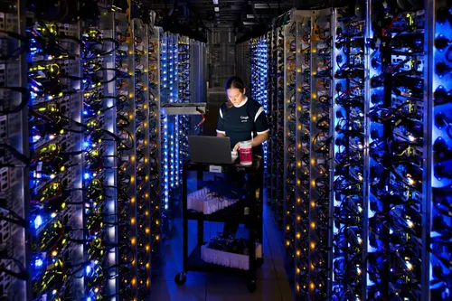 A Google Cloud worker diagnoses a problem in the middle of a large rack of servers.