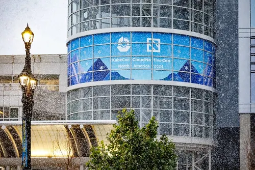 Snow falls in Salt Lake City, Utah, in front of a sign promoting KubeCon North America 2024.