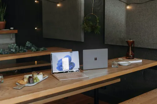 Two Microsoft laptops left open and unattended at a table. Patch Tuesday includes a Desktop Windows Manager zero day