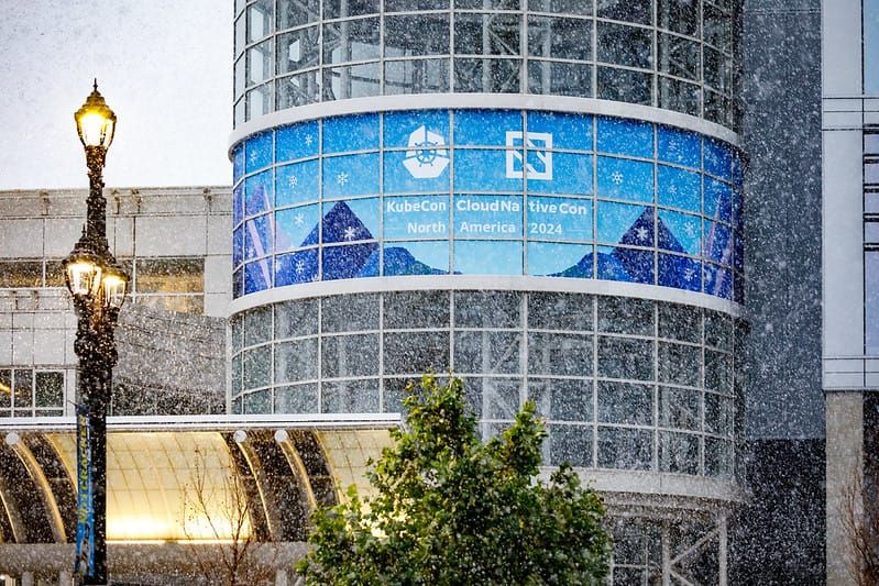 Snow falls in Salt Lake City, Utah, in front of a sign promoting KubeCon North America 2024.
